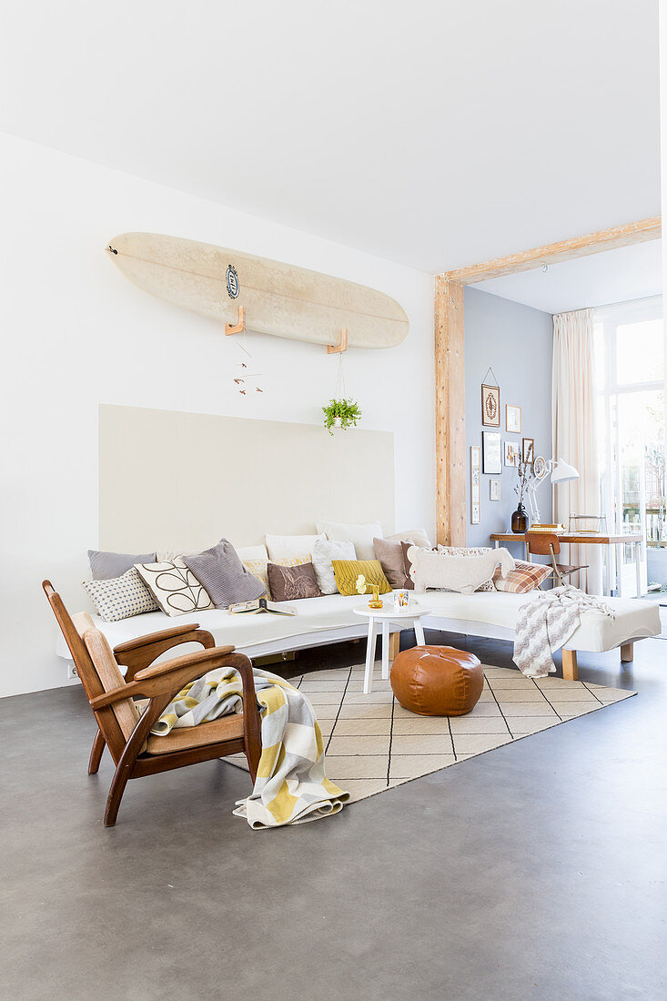 Surfboard on wall above sofa with various scatter cushions