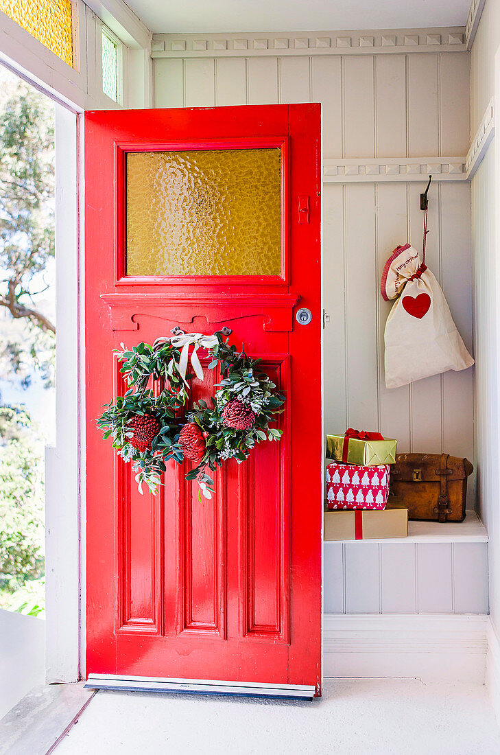 Türkranz mit Protea an roter Haustür zum Windfang mit Geschenken