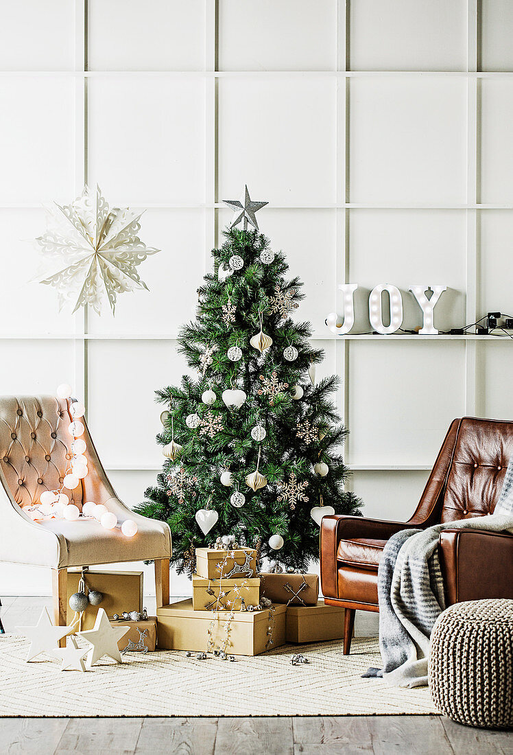 Leather armchairs and gifts around the Christmas tree in front of a cassette wall