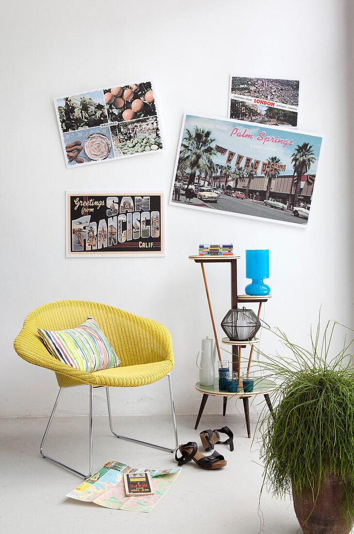 Huge postcards on wall above yellow easy chair and etagere