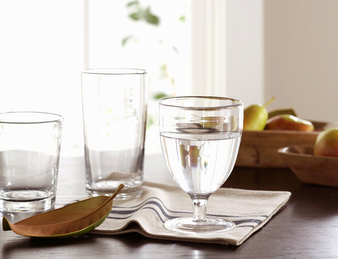 Glasses of water, striped napkins and fruit on table