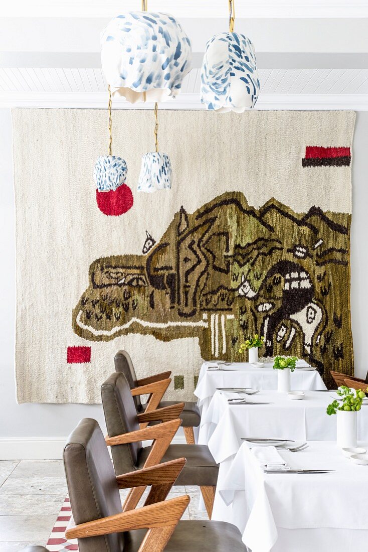 Set tables in restaurant with abstract wall hanging in background