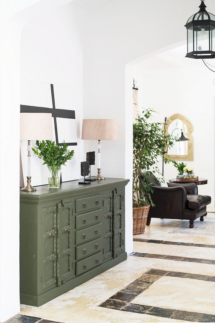 Olive-green chest of drawers between two arched open doorways
