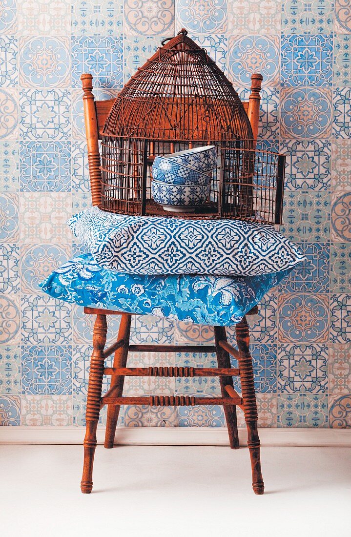 Blue and white, patterned still-life arrangement on chair against wallpaper