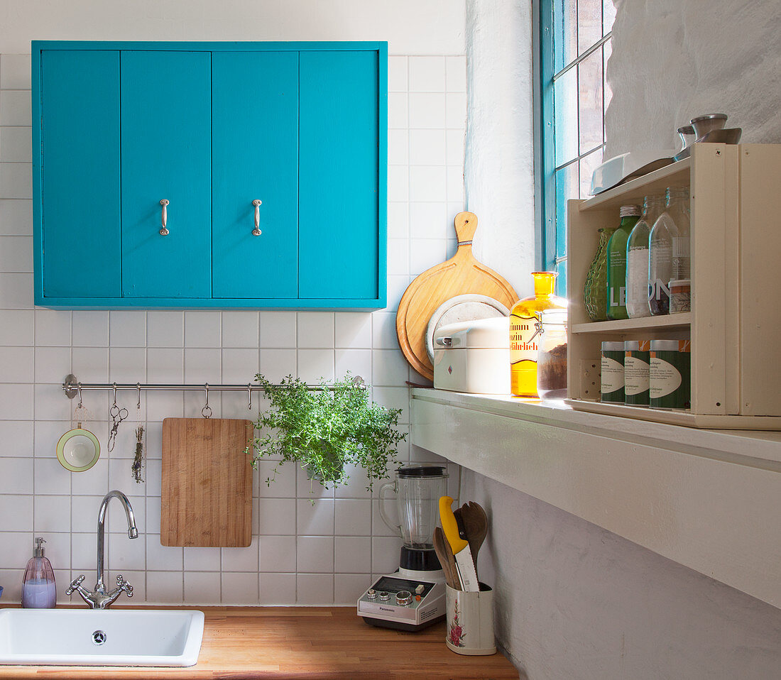 Bright blue kitchen cupboards above sink next to window
