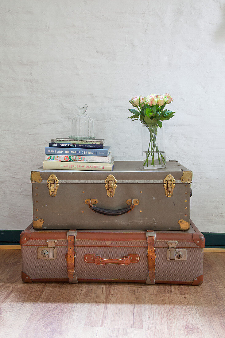 Books and flowers on top of two old, stacked suitcases