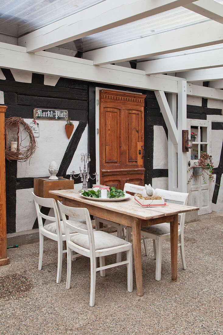 Tisch und Stühle auf überdachter Terrasse vor dem Fachwerkhaus