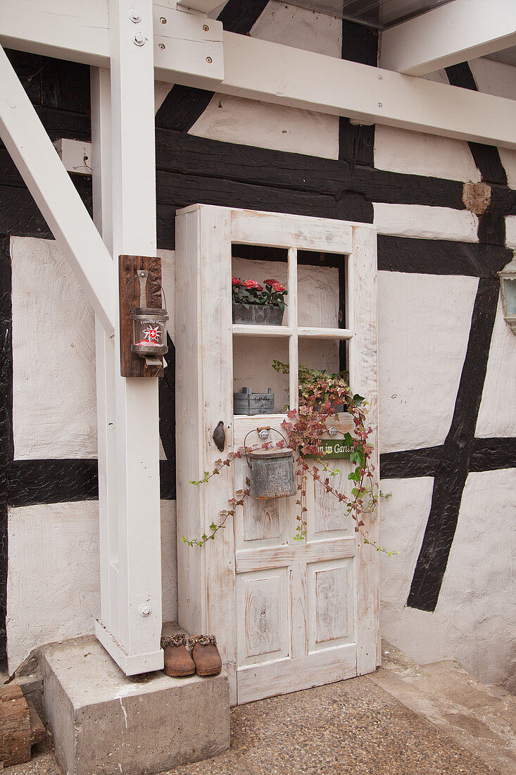 Old wooden door decorated with flowers outside half-timbered house