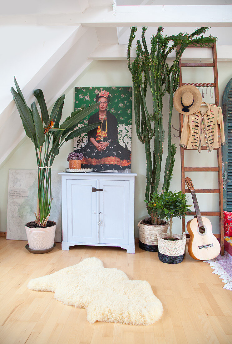 House plants around picture of Frida Kahlo on top of small cabinet