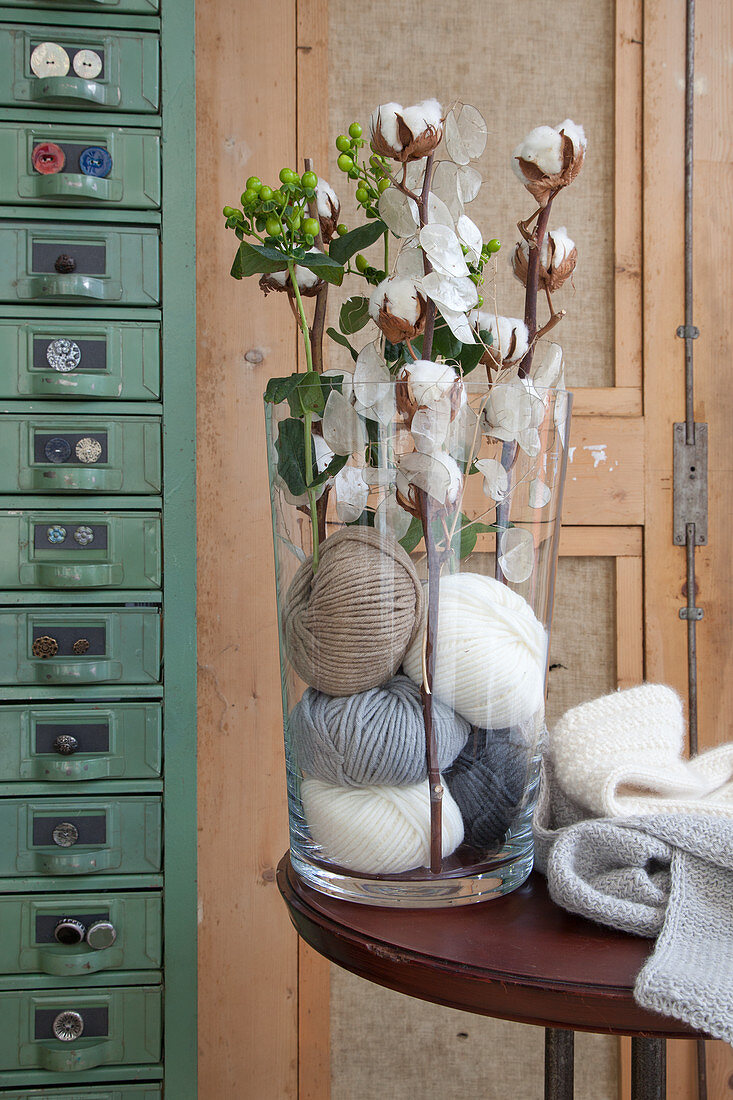 Cotton bolls and honesty in vase filled with balls of wool