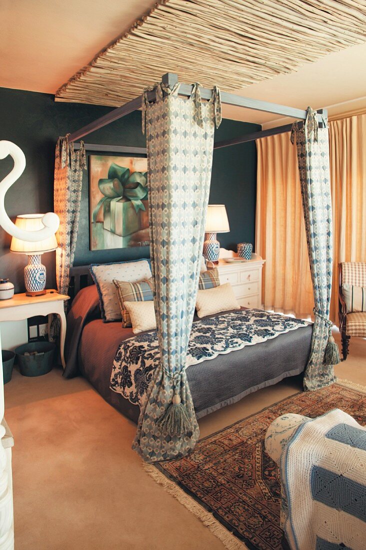 Four-poster bed and petrol-blue wall in bedroom