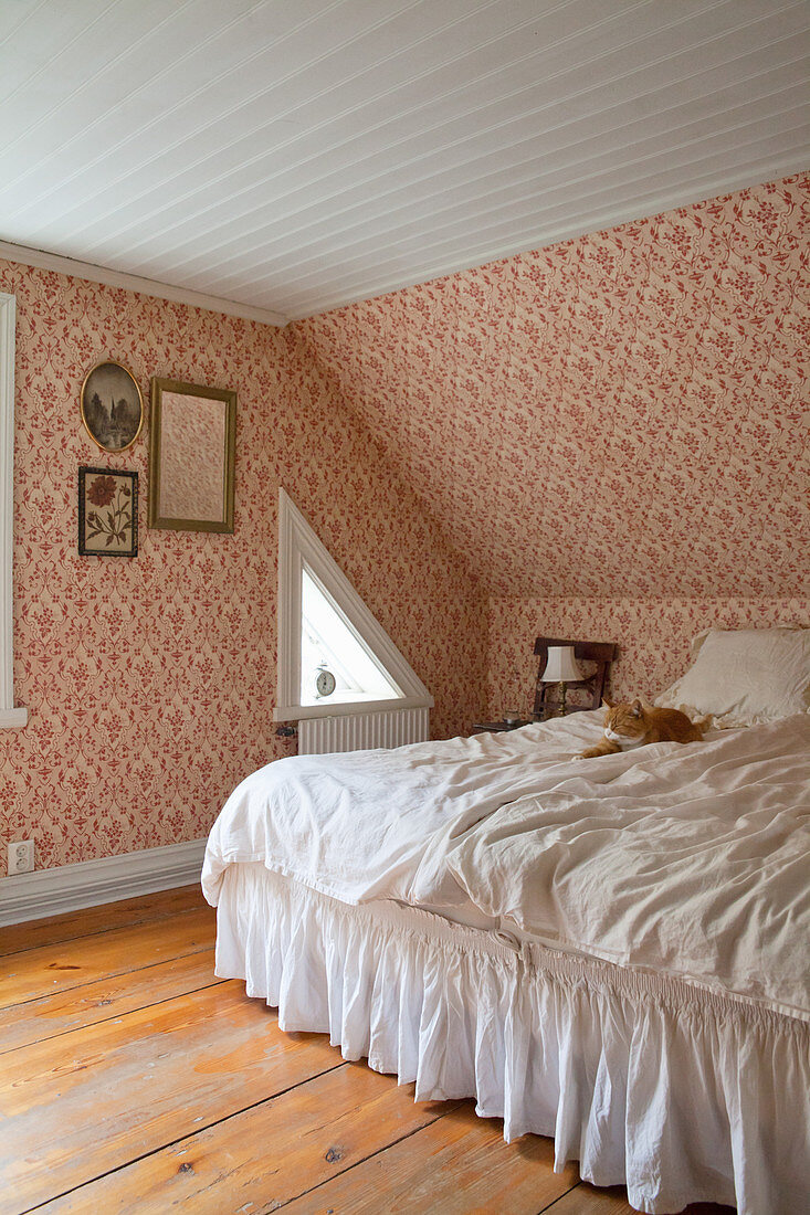 Weißes Bett mit Husse im nostalgische Schlafzimmer mit Dachschräge