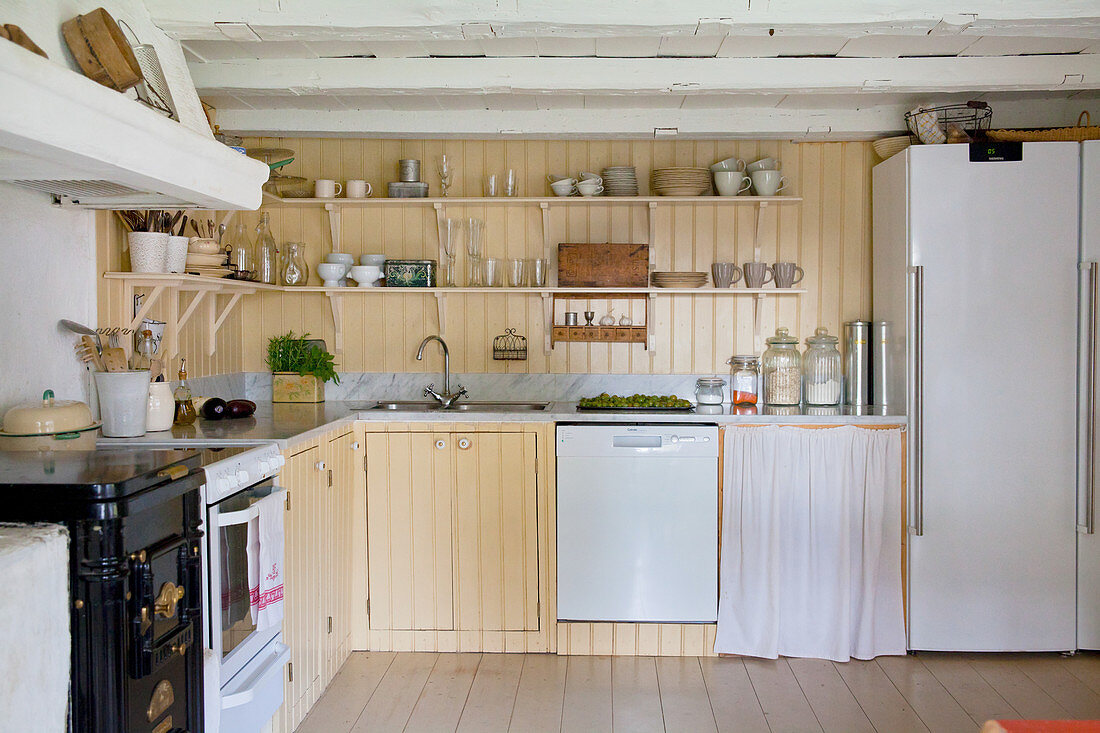 Shelves and yellow wall panelling in country-house kitchen