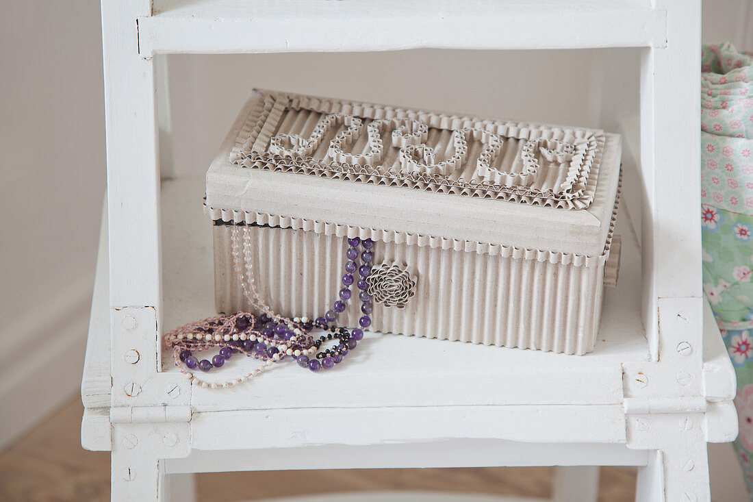 Schmuckschatulle aus Wellpappe mit Perlenketten auf einer Leiter