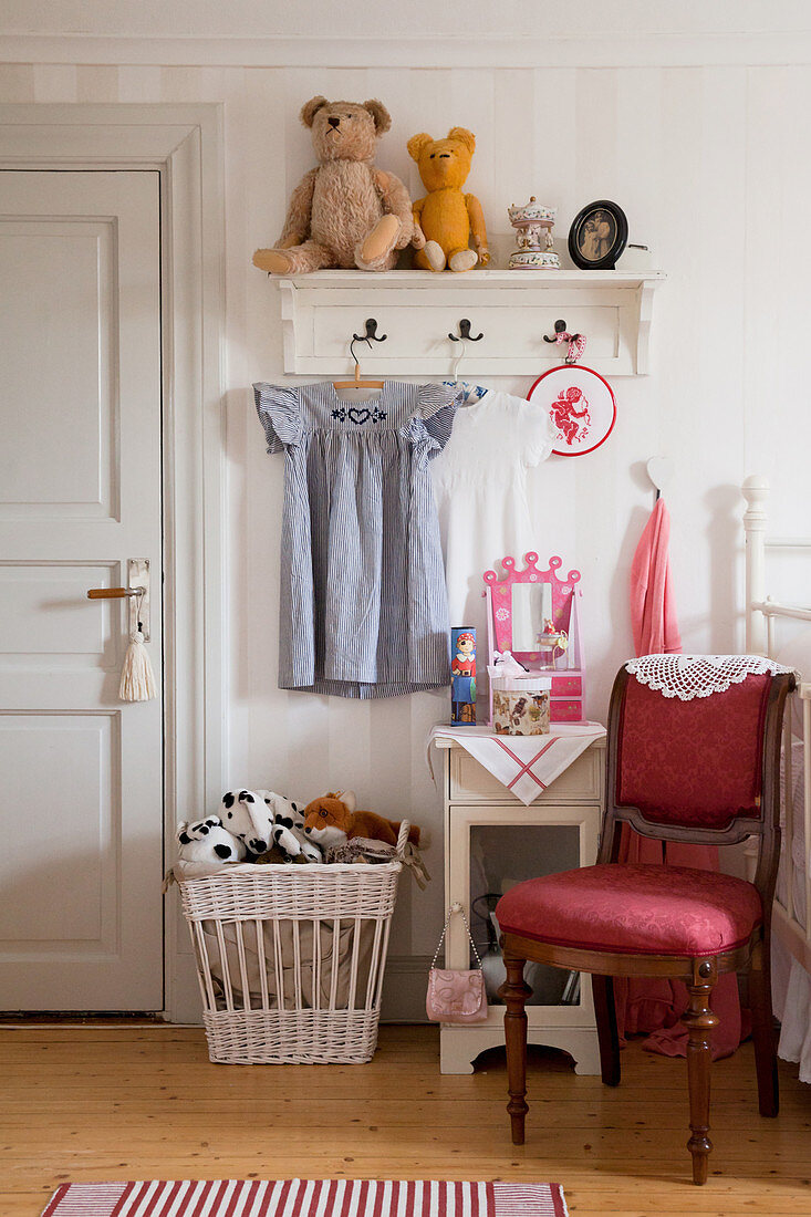 Red upholstered chair in front of coat rack in classic child's bedroom