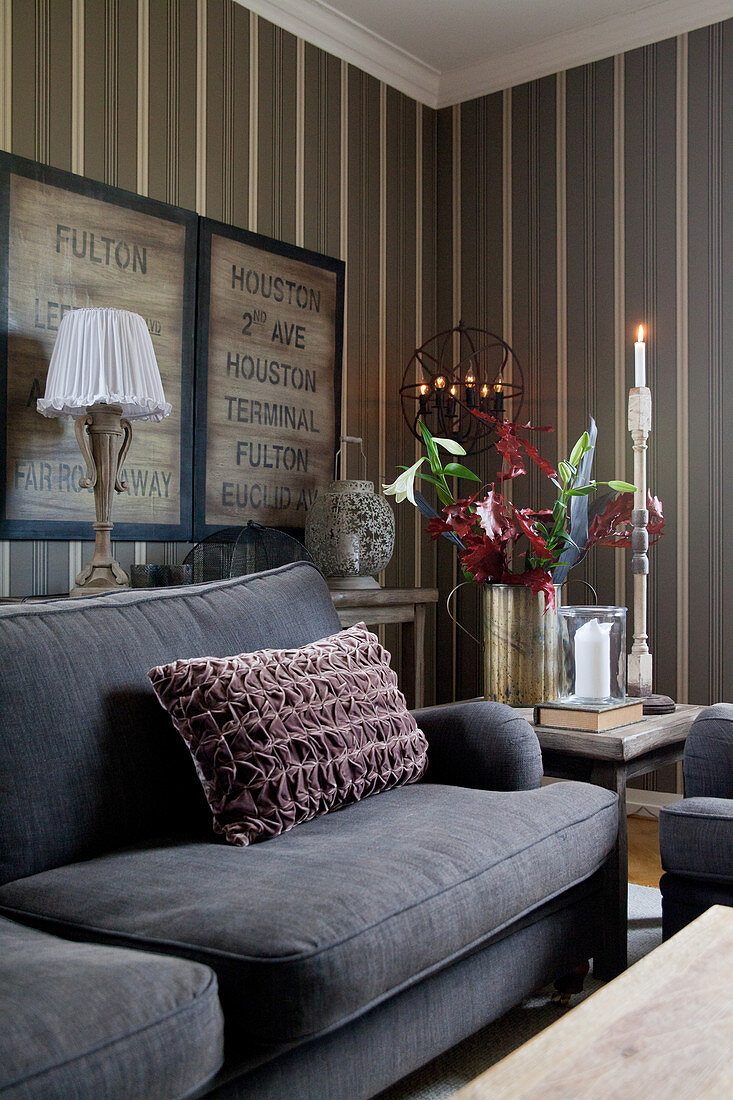Samtkissen auf grauem Sofa im gemütlichen Wohnzimmer mit gestreifter Tapete