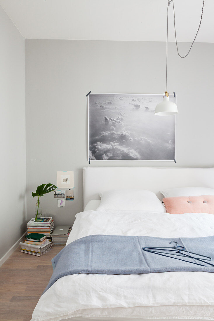 Poster mit Wolken über dem Bett im pastellfarbenen Schlafzimmer
