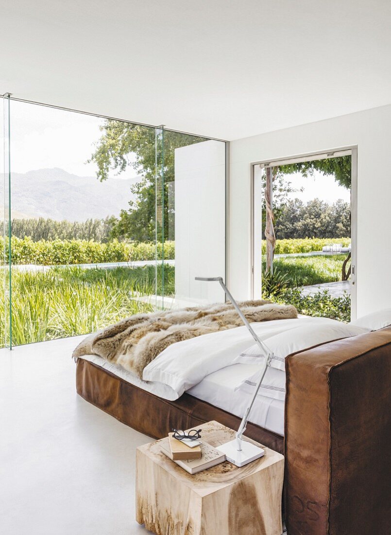 Minimalistisches Schlafzimmer mit Lederbett und Landschaftsblick