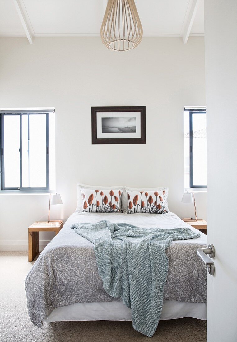 Bed flanked by two windows in simple bedroom
