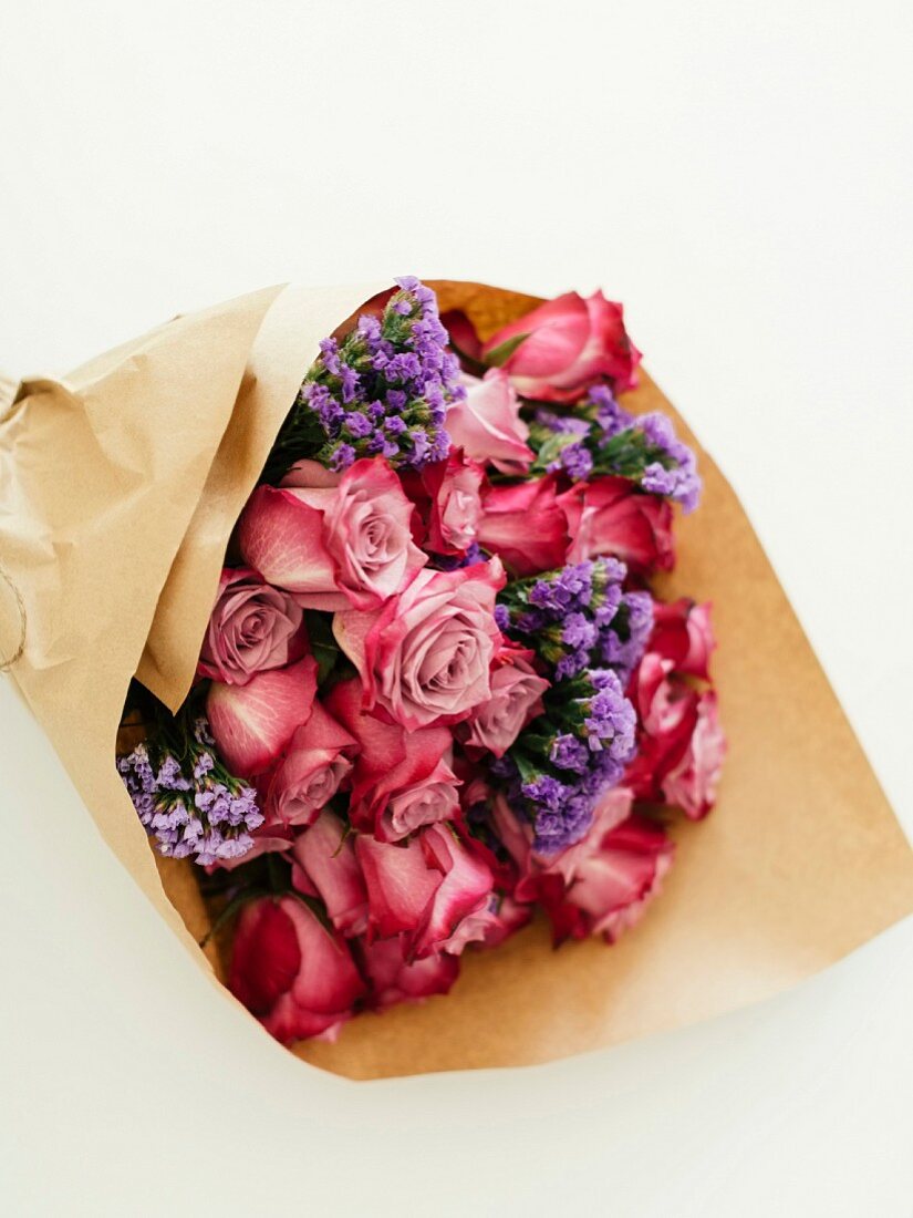 Bouquet of roses and sea lavender wrapped in brown paper