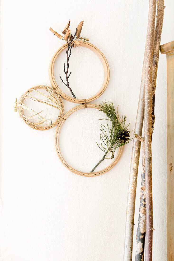 Arrangement of twigs and straw in embroidery frames on wall