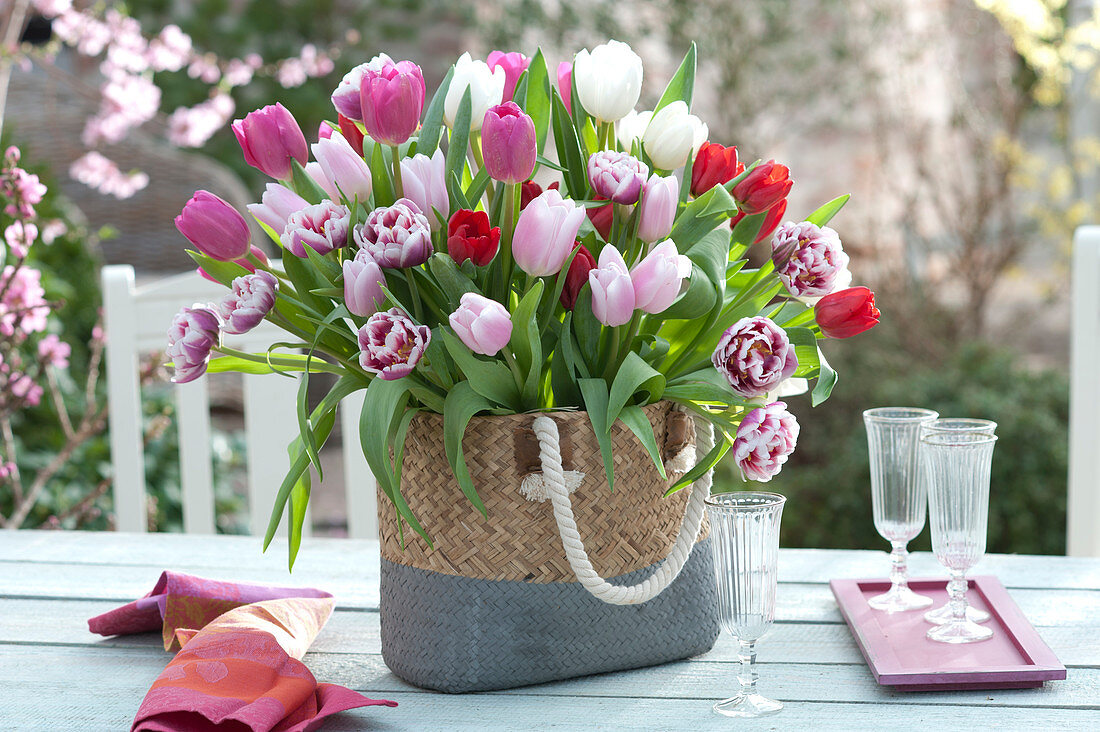 Üppiger Strauß aus gemischten Tulipa ( Tulpen ) in Flechttasche