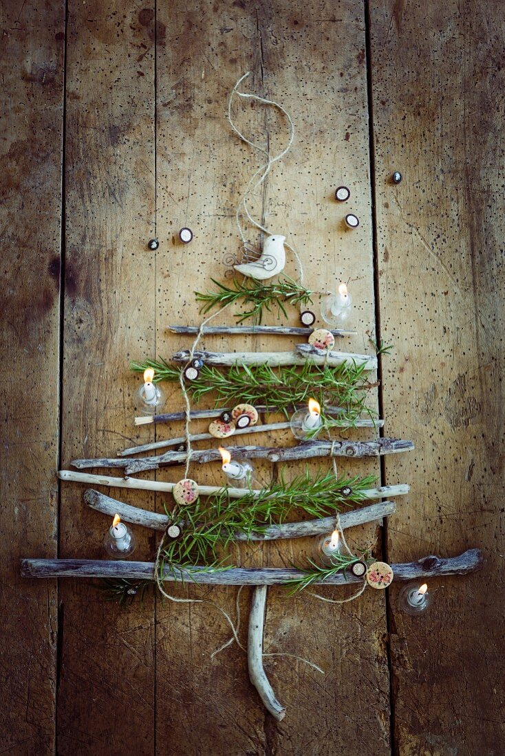 Rustikaler Weihnachtsbaum aus Zweigen an Holzwand