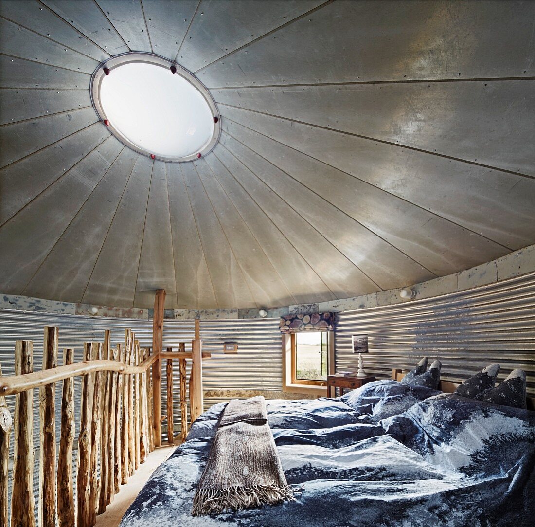 Schlafzimmer in umgebautem Getreidesilo mit Oberlicht und rustikalem Holzgeländer