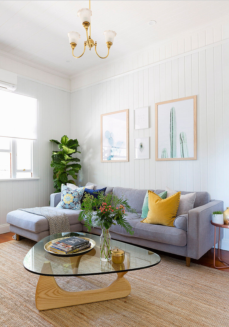 Designertisch vor grauem Sofa im Wohnzimmer mit Wandverkleidung