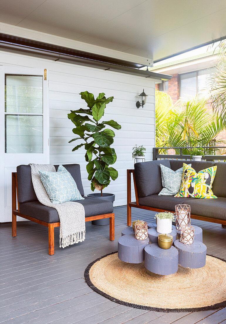 Wooden seating area with gray upholstery on the veranda
