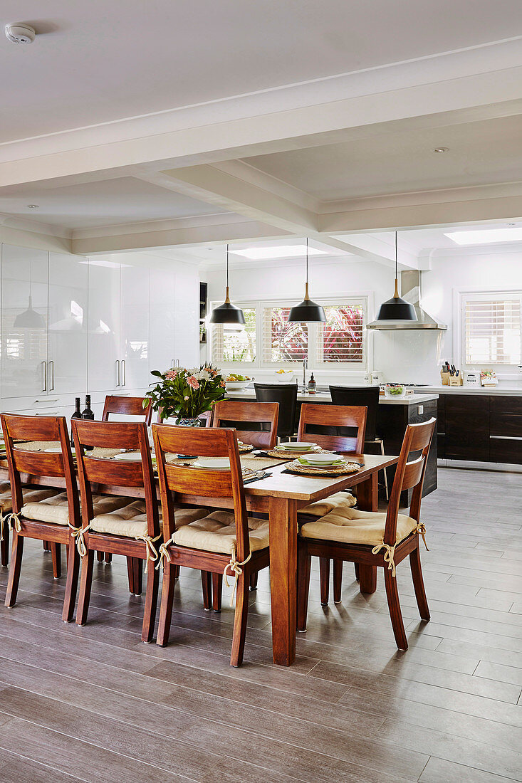 Essbereich mit Holztisch und Stühlen, im Hintergrund offene Küche mit Porzellan-Bodenfliesen in Holzoptik