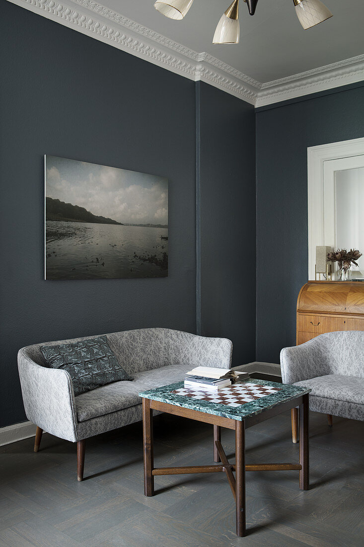 Sofa und Sessel um einen Schachtisch vor grauer Wand