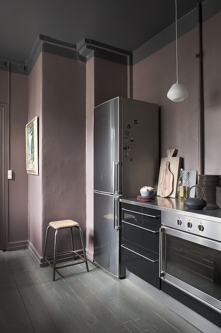 Auberginefarbene Wände in dunkler Küche mit schwarzen Fronten