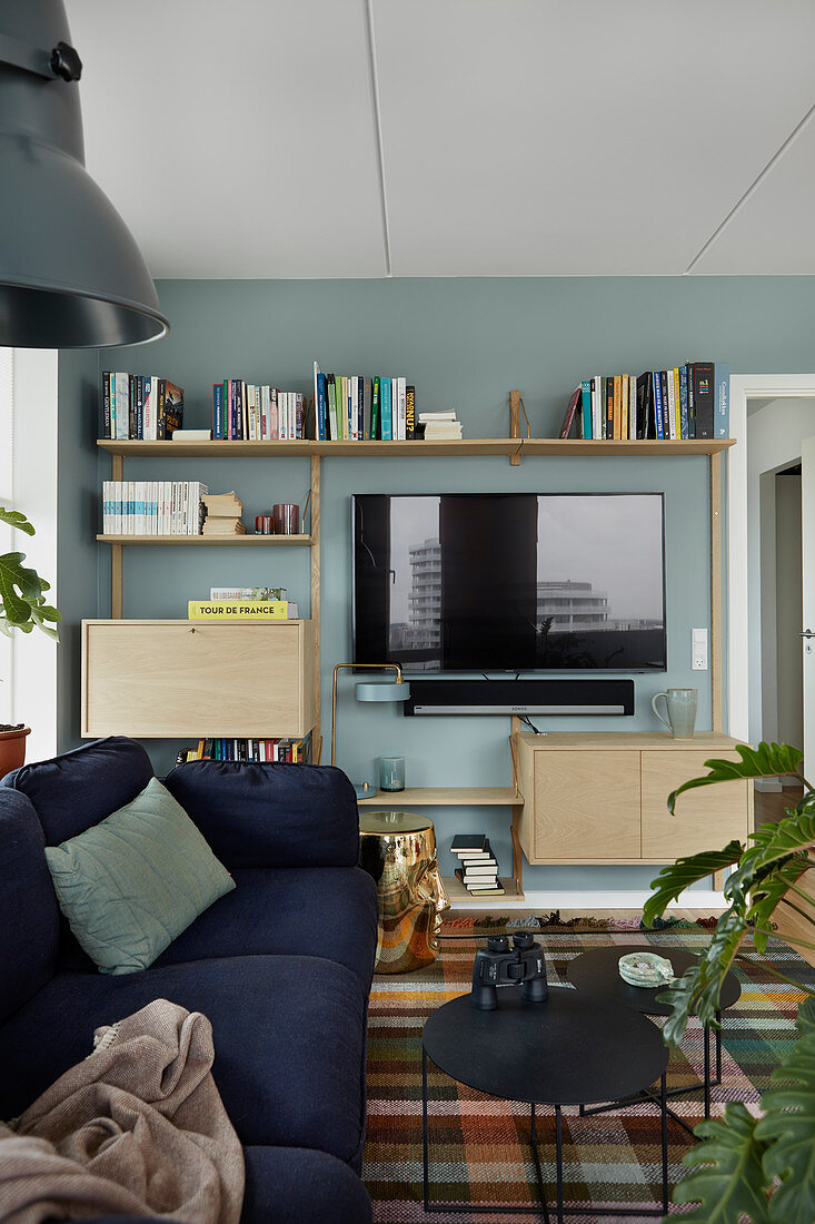 Fernseher und Wandregal an blauer Wand im Wohnzimmer