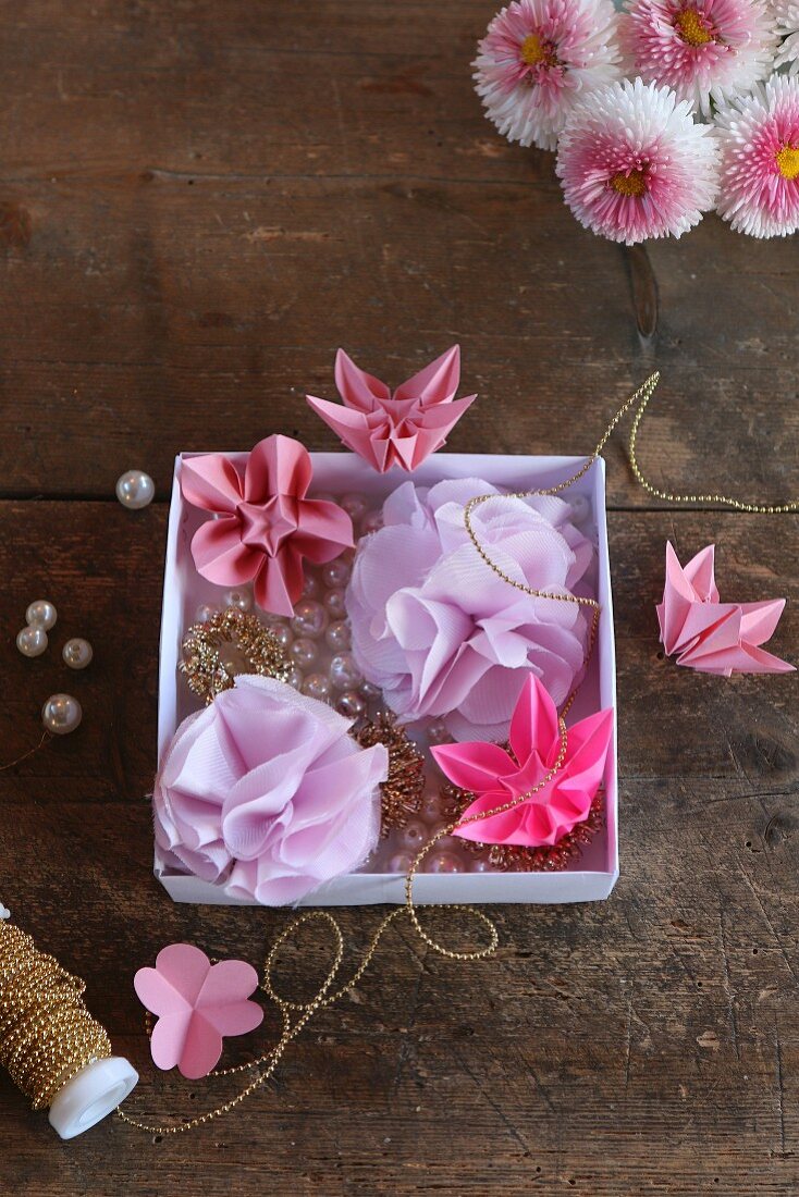 Rosafarbene Origamiblumen und lilafarbene Stoffblumen