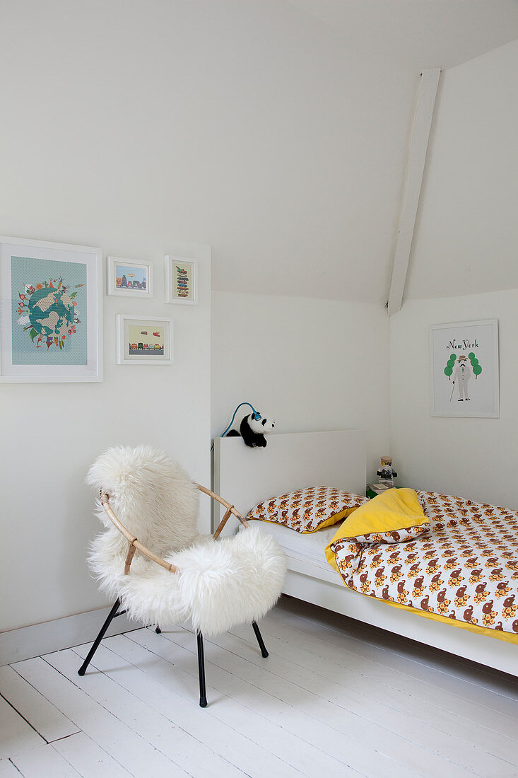 Sheepskin on chair next to bed in child's bedroom decorated entirely in white