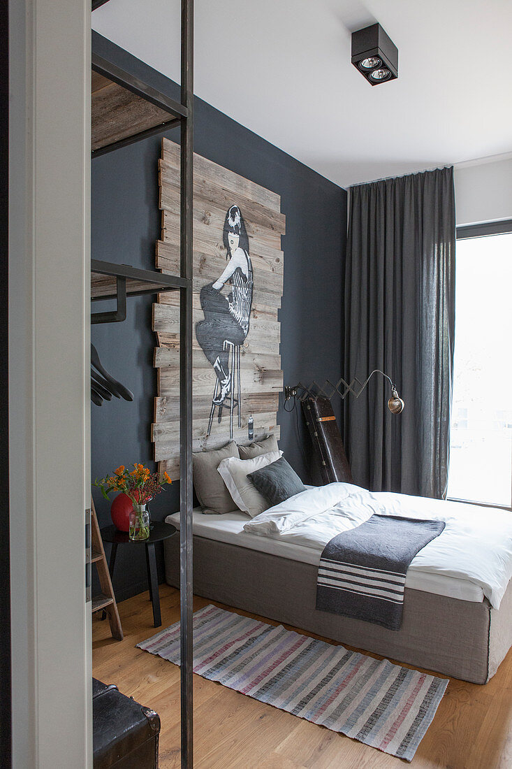 Bedroom in shades of grey with artwork painted on wooden boards above bed
