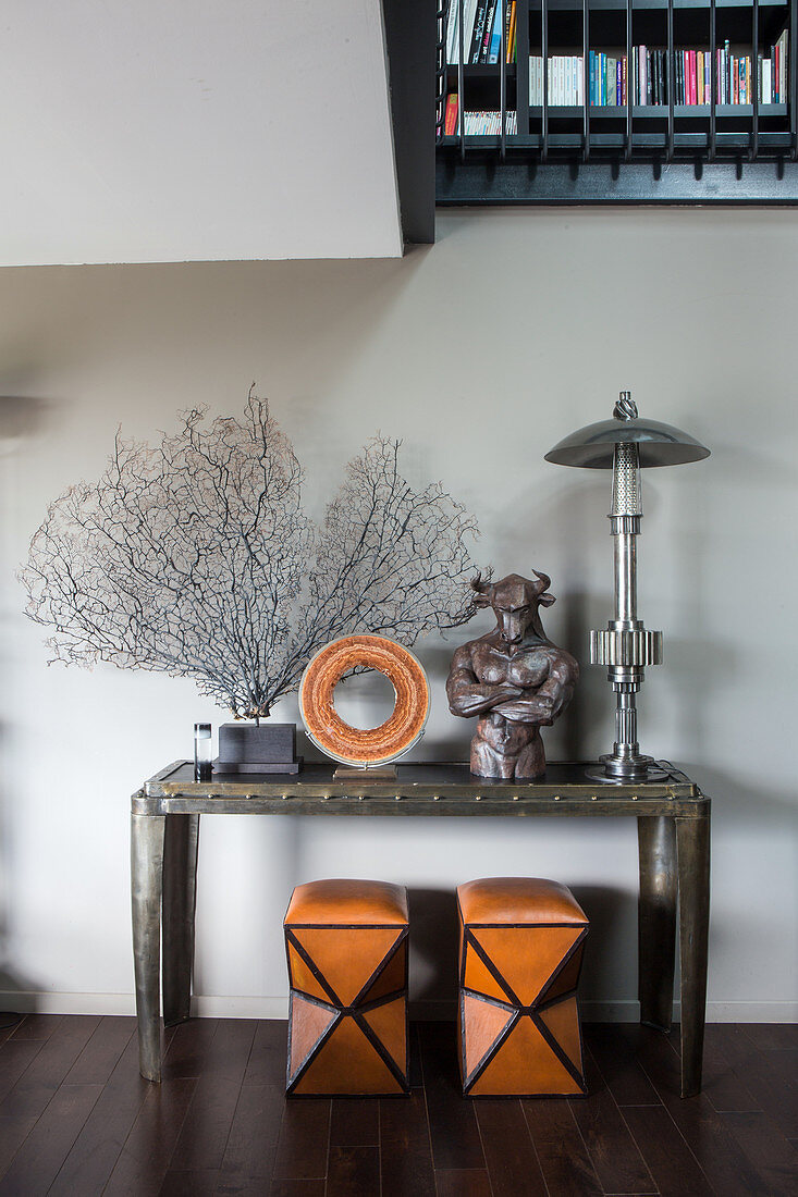 Two stools below corals and sculptures on console table