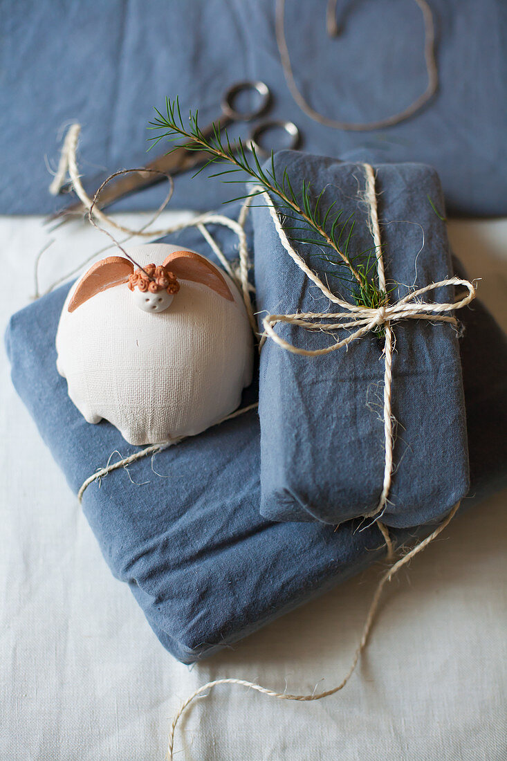 Pottery angel on gifts wrapped in blue fabric