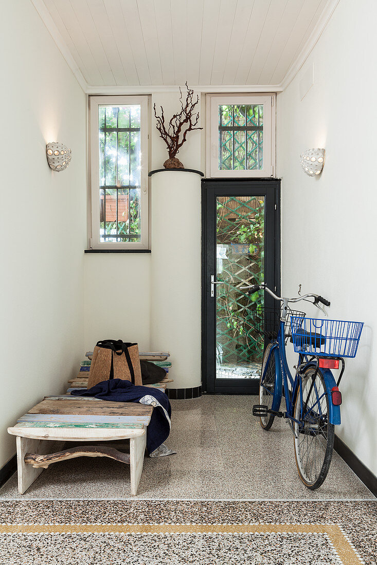 Blaues Fahrrad und eine Strandliege im Eingang mit Terrazzoboden