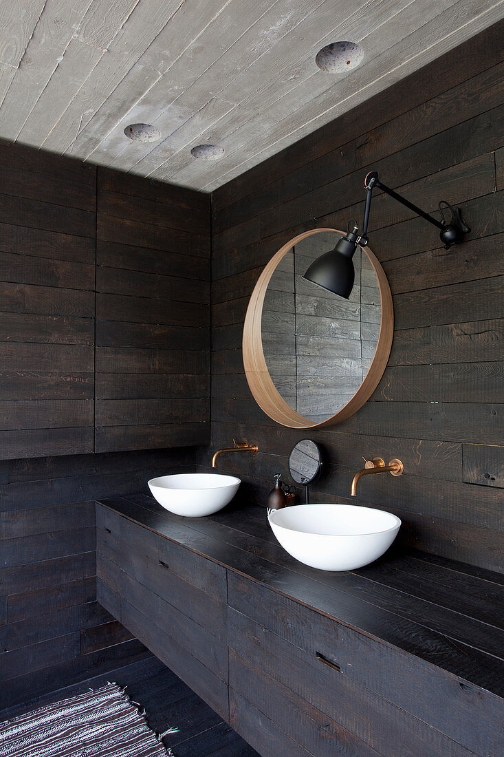 Two countertop sinks in bathroom with dark wooden walls