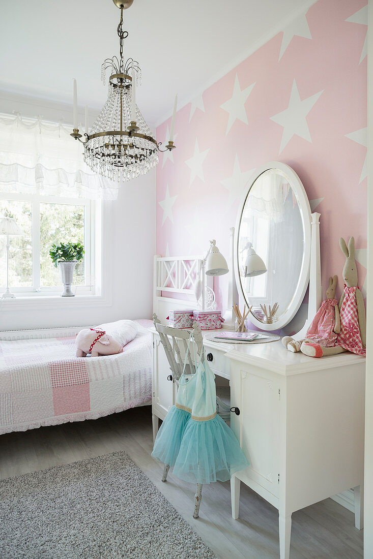 White dressing table with mirror in girl's bedroom with star-patterned wallpaper