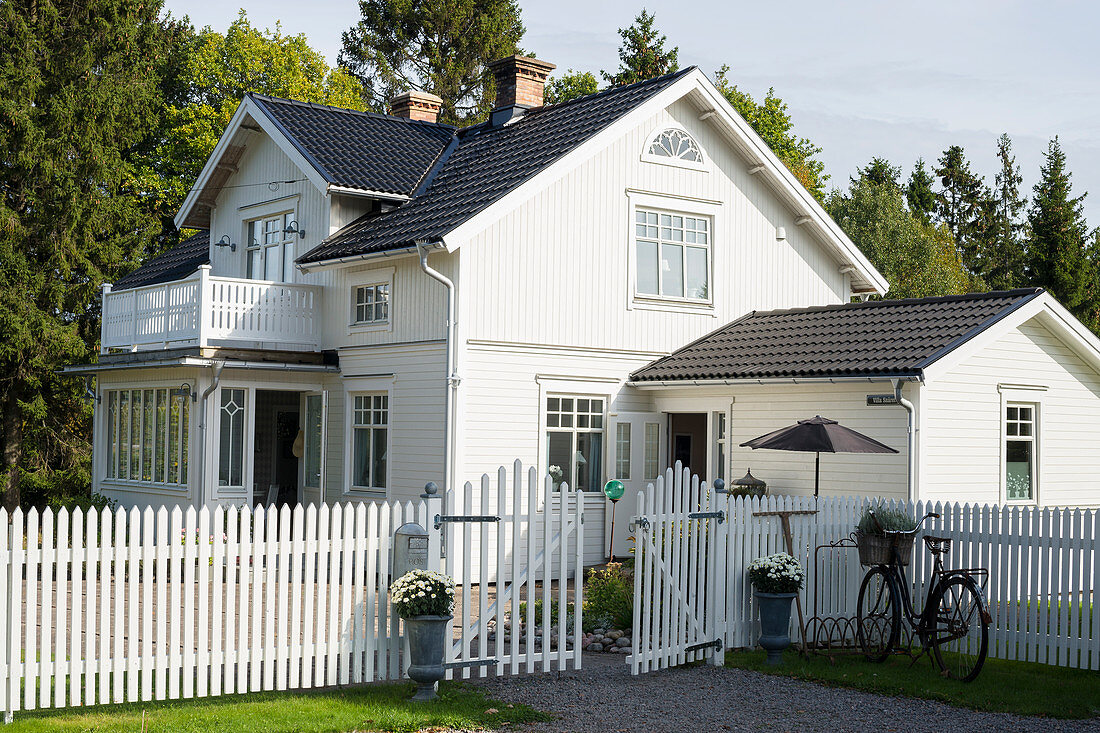 Picket fence around white Swedish house with black roof
