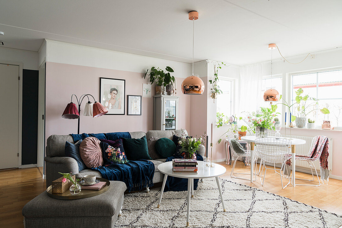 Graues Sofa und Esstisch im Wohnraum mit rosafarbener Wand