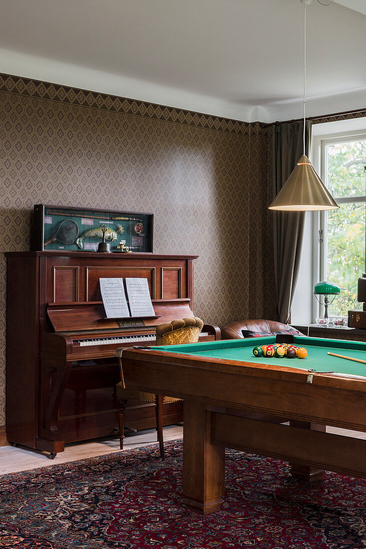 Piano and pool table in masculine living room