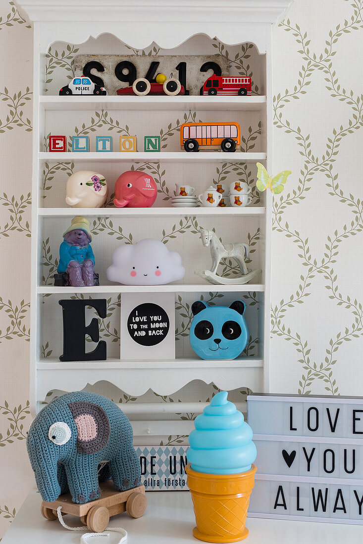 Toys on shelves mounted on wall with patterned wallpaper in child's bedroom