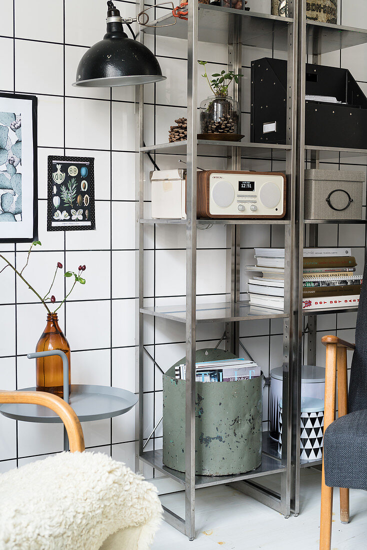 Vintage accessories and retro radio on metal shelving against tiled wall
