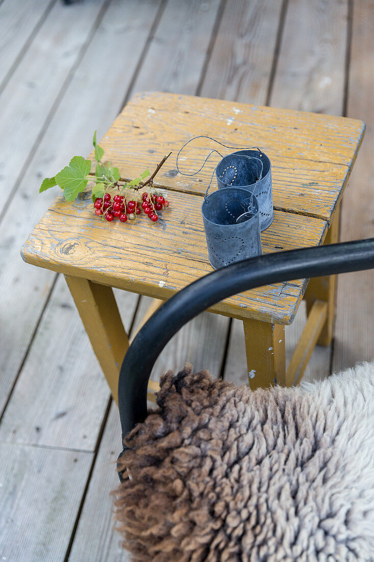 Metal candle lanterns and sprig of redcurrants on stool