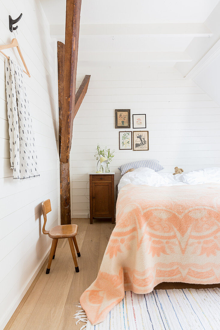 Apricotfarbene Tagesdecke auf dem Bett im ländlichen Schlafzimmer