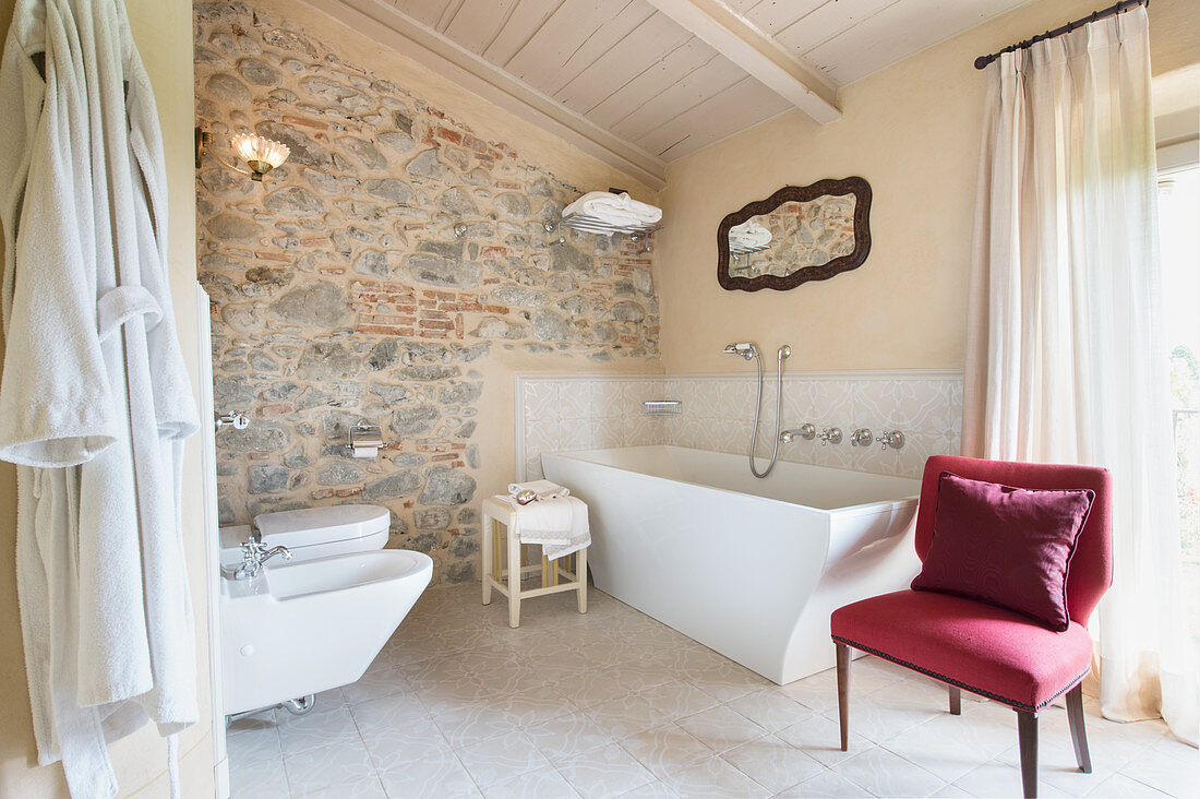 Curved bathtub and stone wall in elegant bathroom